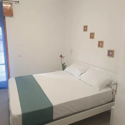 a bedroom with a white bed with a green and blue blanket at Cà Porto-Rooms with Balcony&Terrace in Santa Flavia