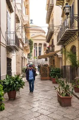 a man walking down a street in an alley at B&B del Massimo in Palermo