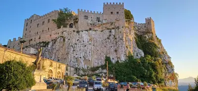 a castle on the side of a mountain with cars parked at Casa del Vecchio Borgo in Caccamo