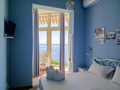 a blue room with a bed and a large window at Case Nereidi 3 in Porticello
