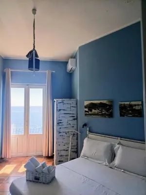 a bedroom with a bed and a blue wall at Case Nereidi 3 in Porticello