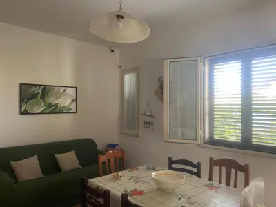 a living room with a table and a green couch at Villetta SCHIRÒ - BAGNASCO in Campofelice di Roccella