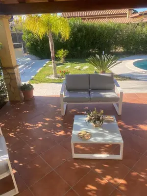 a patio with a couch and a coffee table at Villetta SCHIRÒ - BAGNASCO in Campofelice di Roccella