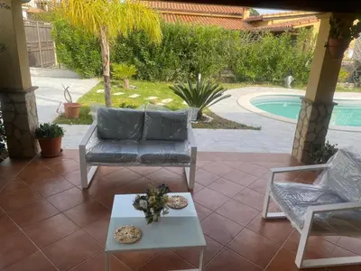 a patio with a couch and a table and a pool at Villetta SCHIRÒ - BAGNASCO in Campofelice di Roccella