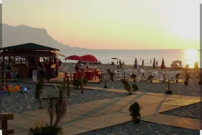 a beach with tables and umbrellas and the ocean at Darling in Capaci