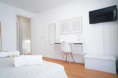 a white room with a bed and a tv on the wall at Encanto Apartment in Palermo