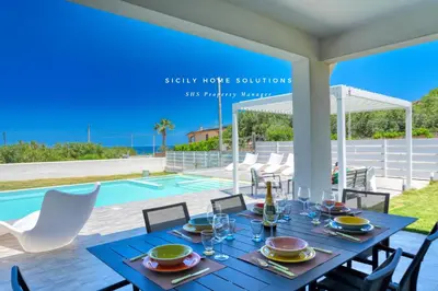 a dining table with a bottle of wine and glasses at Villa Stella con piscina privata 500 mt dal mare By Sicily Home Solutions in Trappeto
