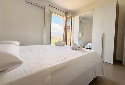 a bedroom with a white bed with a large window at Appartamento La Duchessa in Campofelice di Roccella