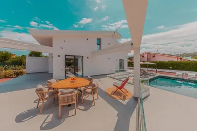 a patio with a table and chairs and a pool at NAHIA Collection Villa in Campofelice di Roccella