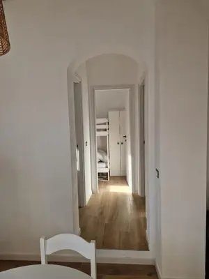 a hallway with white walls and a table and a chair at Mammì in Balestrate
