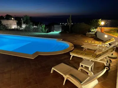 a swimming pool with chaise lounges and chairs around it at night at Pool & Panoramic Villa - 9 mins city center in Palermo