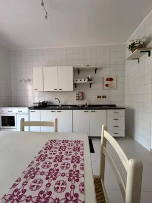 a kitchen with white cabinets and a table and chairs at La casa dei Nonni in Santa Flavia