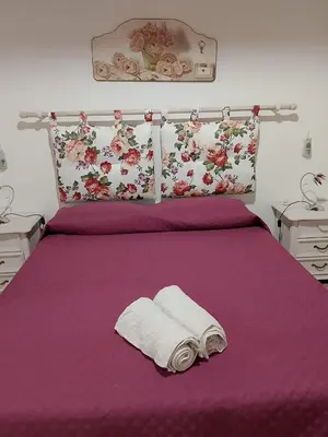 a bed with a purple bedspread and two towels on it at La Casetta Di Liù in Villagrazia