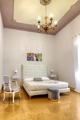 a bedroom with a large bed and a chandelier at IG Holiday in Cinisi