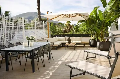 a patio with tables and chairs and an umbrella at Villa Finch Mondello in Palermo