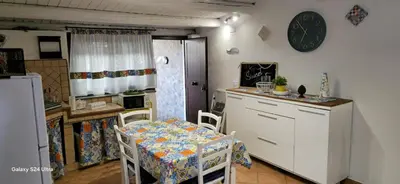 a kitchen with a table and chairs and a kitchen with a clock at la casetta di nin e gian mondello in Palermo