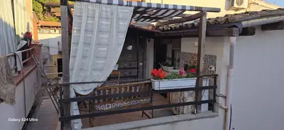 a balcony with a window with a curtain and flowers at la casetta di nin e gian mondello in Palermo