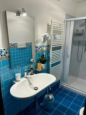 a blue tiled bathroom with a sink and a shower at La Casetta Panoramica in Palermo