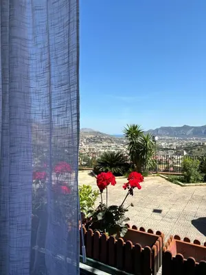 a balcony with red flowers and a view of a city at La Casetta Panoramica in Palermo