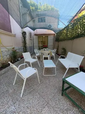 a patio with white chairs and a table at Villino Sirene Mondello in Palermo