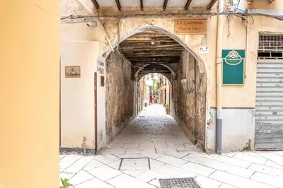 an alley way in an old building with an archway at Ai Vicoli Ciambra's Alley by Wonderful Italy in Monreale