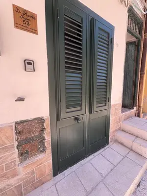 a green door with a sign on the side of a building at LeRoccheRoom in Monreale