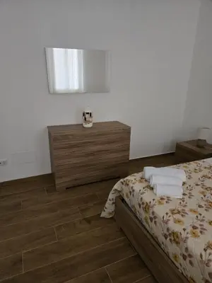 a bedroom with a bed and wooden floors at Nonna Franca GuestHouse in Isola delle Femmine