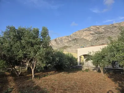 a building with trees and a mountain in the background at Nonna Franca GuestHouse in Isola delle Femmine
