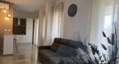 a living room with a couch and a clock on the wall at TramQuility House in Palermo