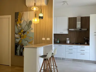 a kitchen with white cabinets and a painting on the wall at TramQuility House in Palermo