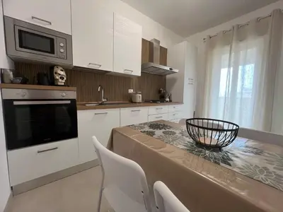 a kitchen with white cabinets and a table with chairs at TramQuility House in Palermo