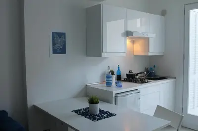 a kitchen with white cabinets and a table with a plant on it at Mondello Suites FLH - Riflessi in Palermo