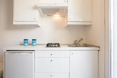 a kitchen with white cabinets and a sink at Mondello Suites FLH - Riflessi in Palermo