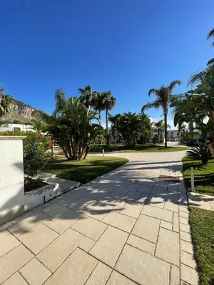 a walkway with palm trees in a park at Le Palme House in Isola delle Femmine