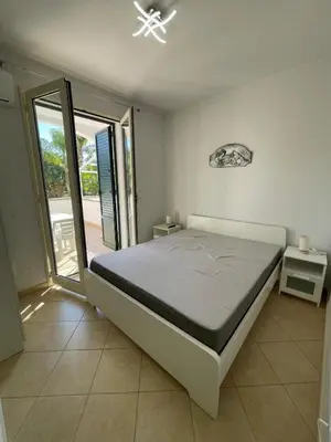 a bedroom with a bed and a sliding glass door at Le Palme House in Isola delle Femmine