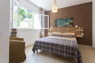 a bedroom with a bed with a plaid blanket and a window at Mondello suites FLH - Posidonia in Palermo