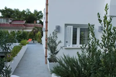 a walkway leading to a white house with plants at Mondello suites FLH - Posidonia in Palermo