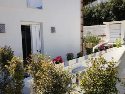 a white house with potted plants on the side of it at Mondello suites FLH - Posidonia in Palermo