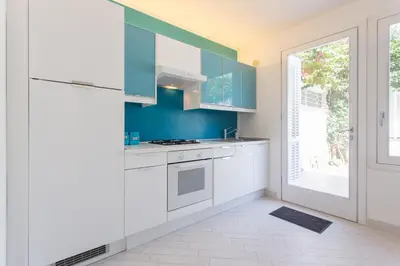 a kitchen with white cabinets and a large window at Mondello Suites FLH - Anemone in Palermo