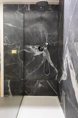 a shower with a black marble wall with a shower head at Dimora Ai Leoni, Suite & Apartments in Palermo
