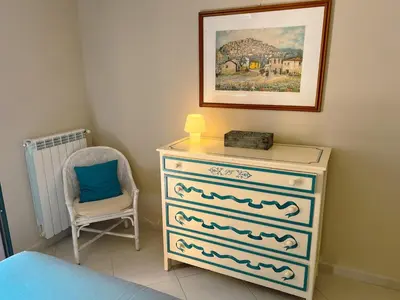a bedroom with a dresser with a lamp and a chair at Belmonte 18 in Palermo