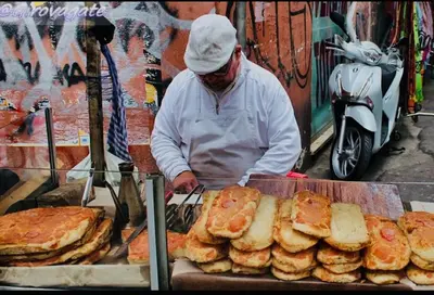 a man is preparing food on a table with bread at Il sole siciliano in Palermo