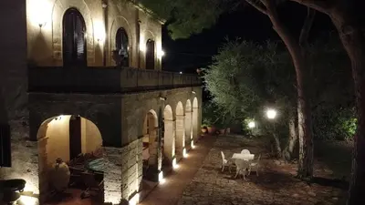 a stone building with a table and chairs at night at Villa Kinisia, antica dimora siciliana in Cinisi