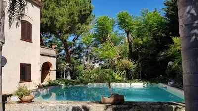 a swimming pool in a yard with trees at Villa Kinisia, antica dimora siciliana in Cinisi