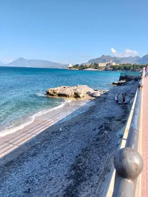 a beach with people sitting on the shore at Il mare negli occhi in Porticello