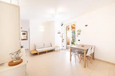 a white living room with a table and a chair at Villa Azzurra in Scopello