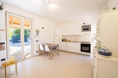 a kitchen with white cabinets and a table with chairs at Villa Azzurra in Scopello