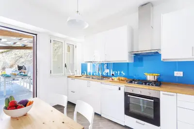 a kitchen with white cabinets and a table with a bowl of fruit at Cava in Scopello