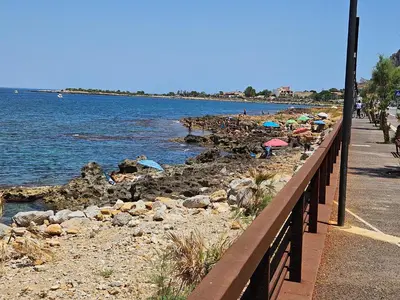 a group of people on the beach with umbrellas at la villetta sul mare in Palermo
