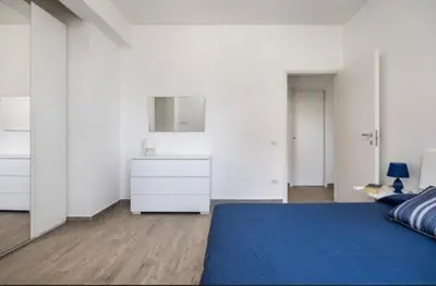 a white bedroom with a blue bed and a dresser at la villetta sul mare in Palermo